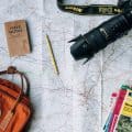 mapa com mochila, máquina footgráfica, livro e lápis em cima